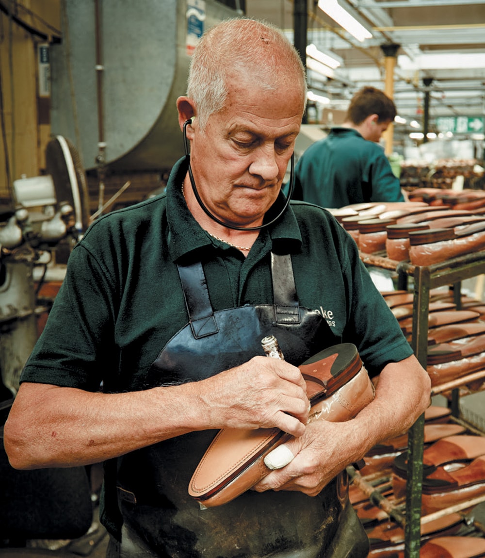 Loake craftsman holding a leather sole English made shoe, working hard on a Loake Factory Repair.