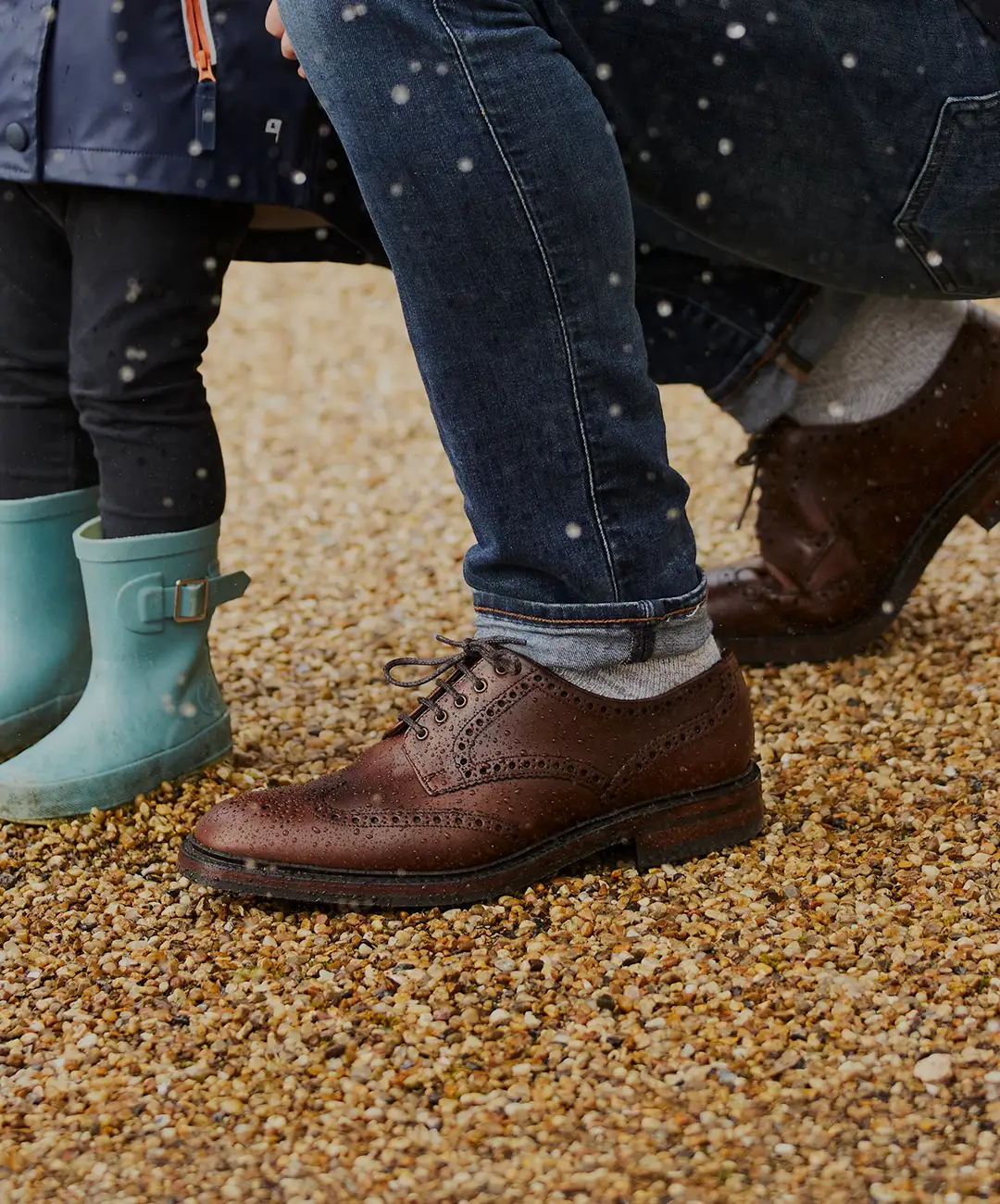 Man standing with his child, with an umbrella up as it is raining. Shoes shown are Chester in brown leather