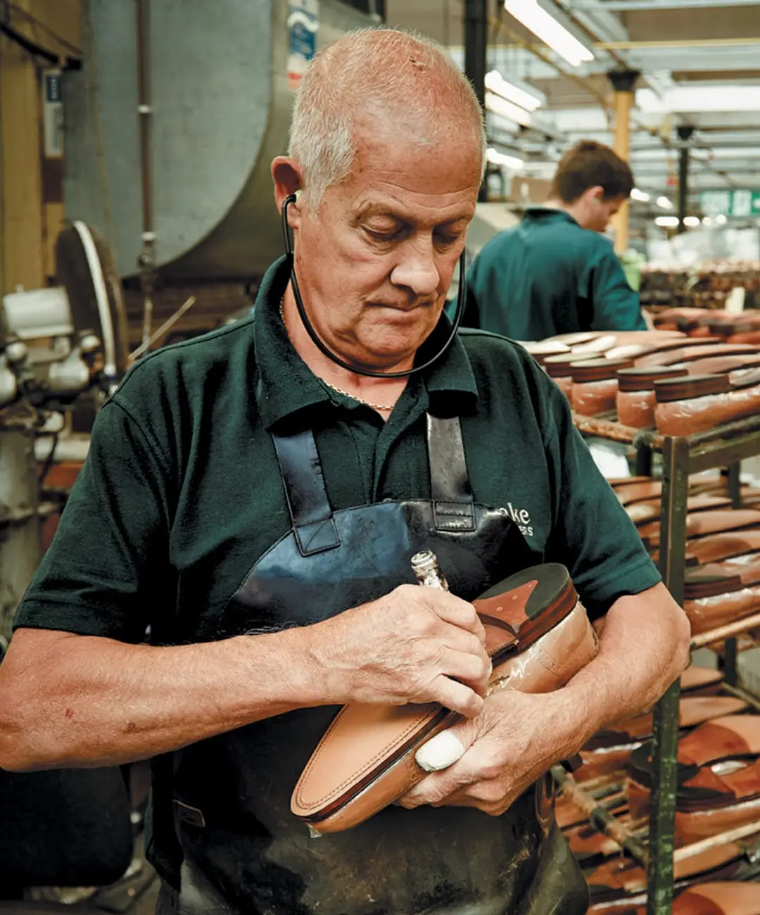 Loake craftsman holding a leather sole English made shoe, working hard on a Loake Factory Repair.