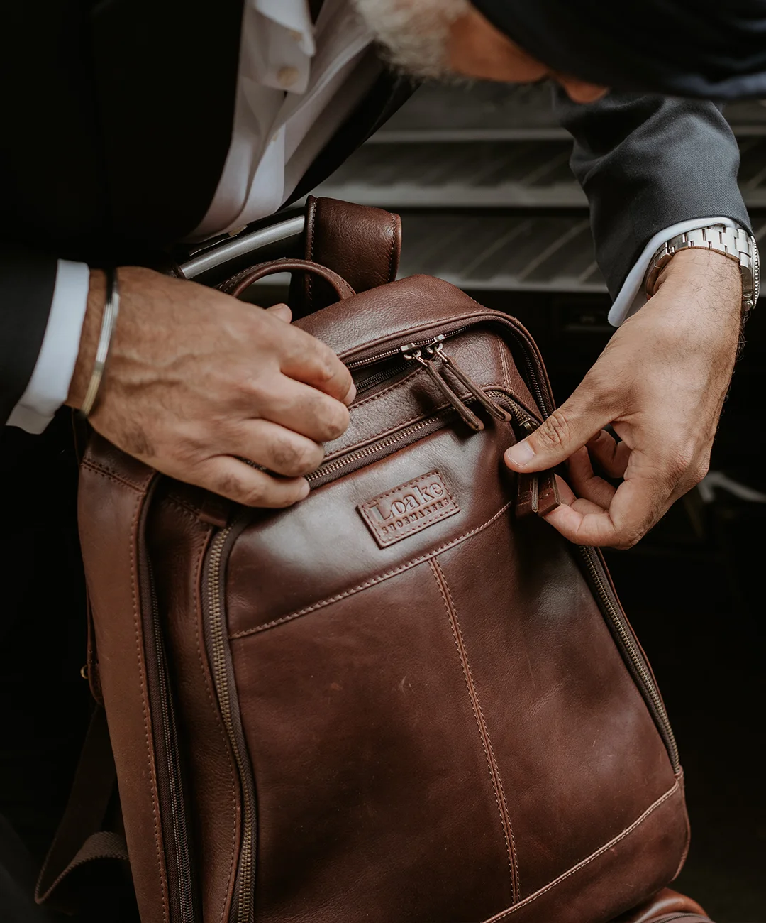 Man zipping up his new Loake brown leather Waterloo backpack, ruck sack or bag