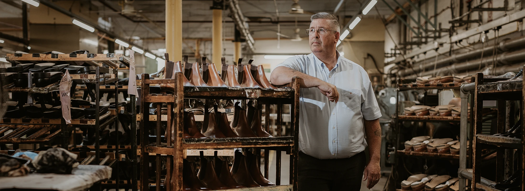 Shoemaker standing in the Loake factory admiring the shoes he has made. Shoes shown are Coppergate in chestnut brown leather