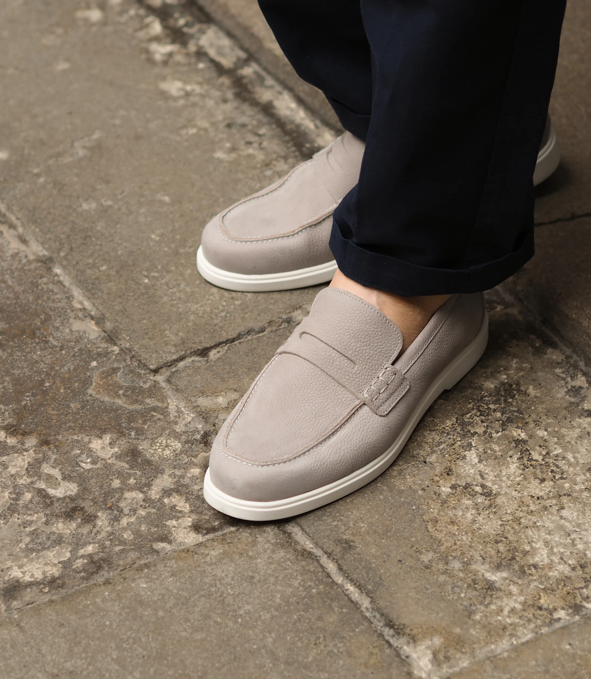 A man wearing navy blue trousers standing on concrete floor, wearing Loake Como Loafers in Grey Nubuck.