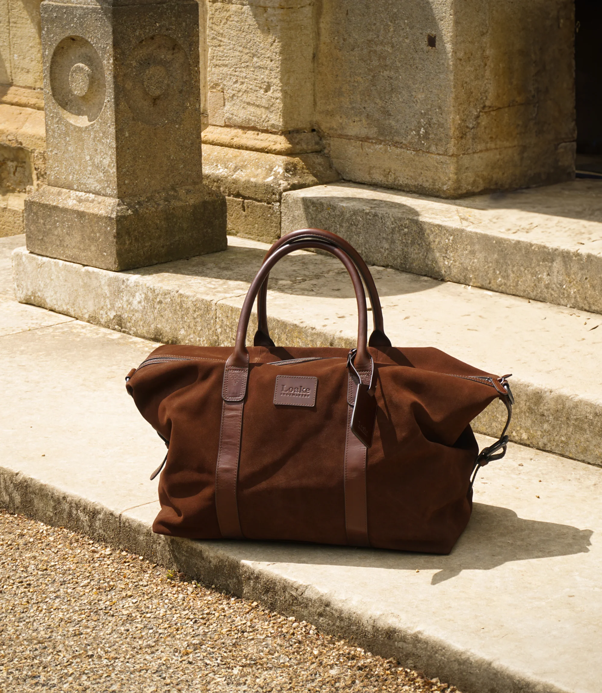 A Loake weekend bag on its own on concrete steps Balmoral Polo Suede.