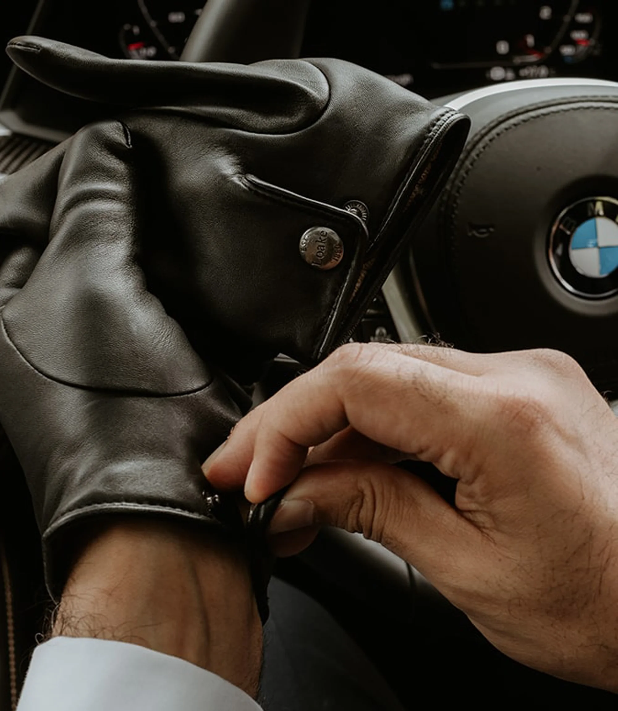 A man in a car behind the wheel wearing his Loake Shackleton Gloves in Black Calf Leather.