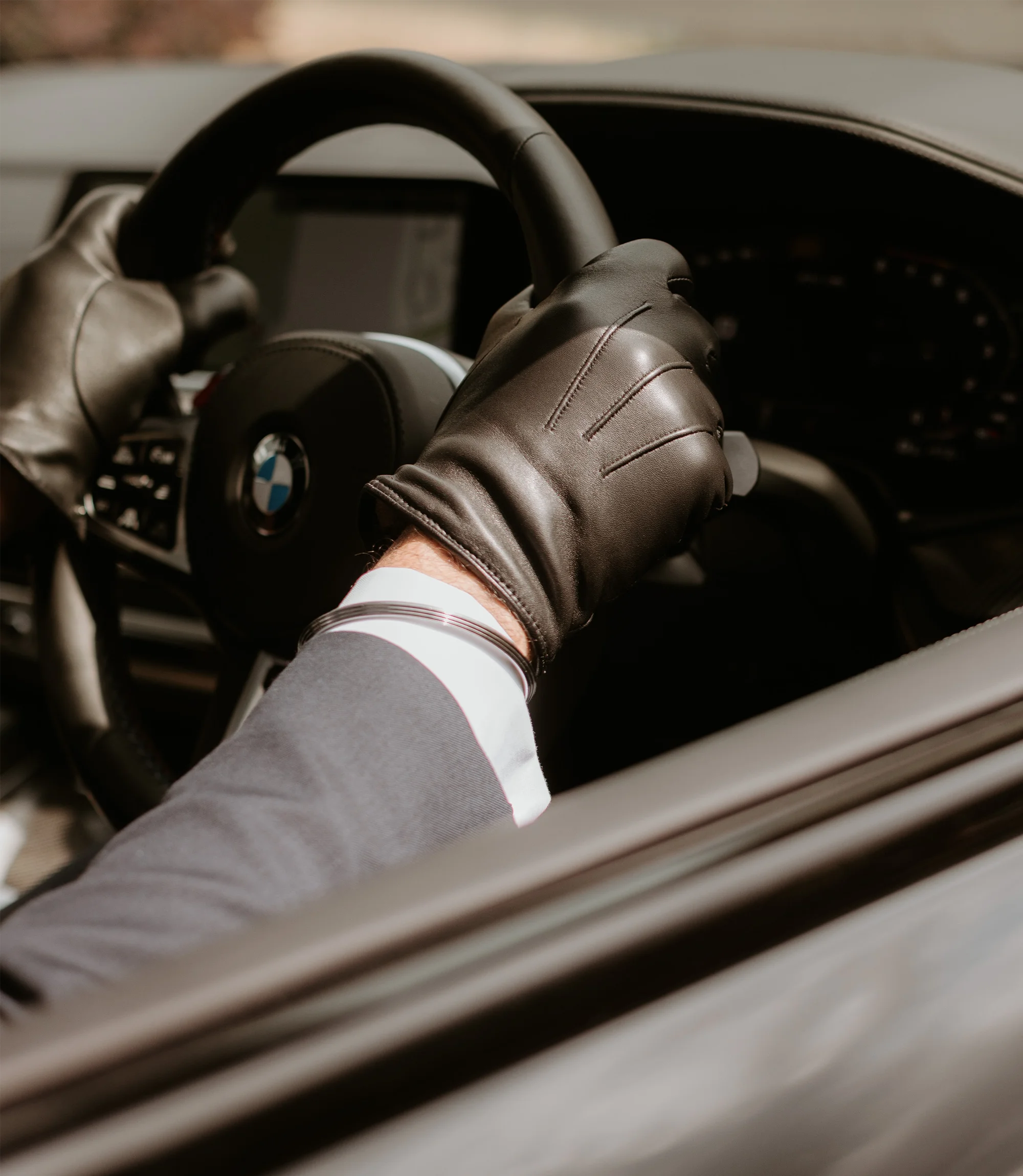A man in a car driving wearing his Loake Shackleton Gloves in Black Calf Leather.