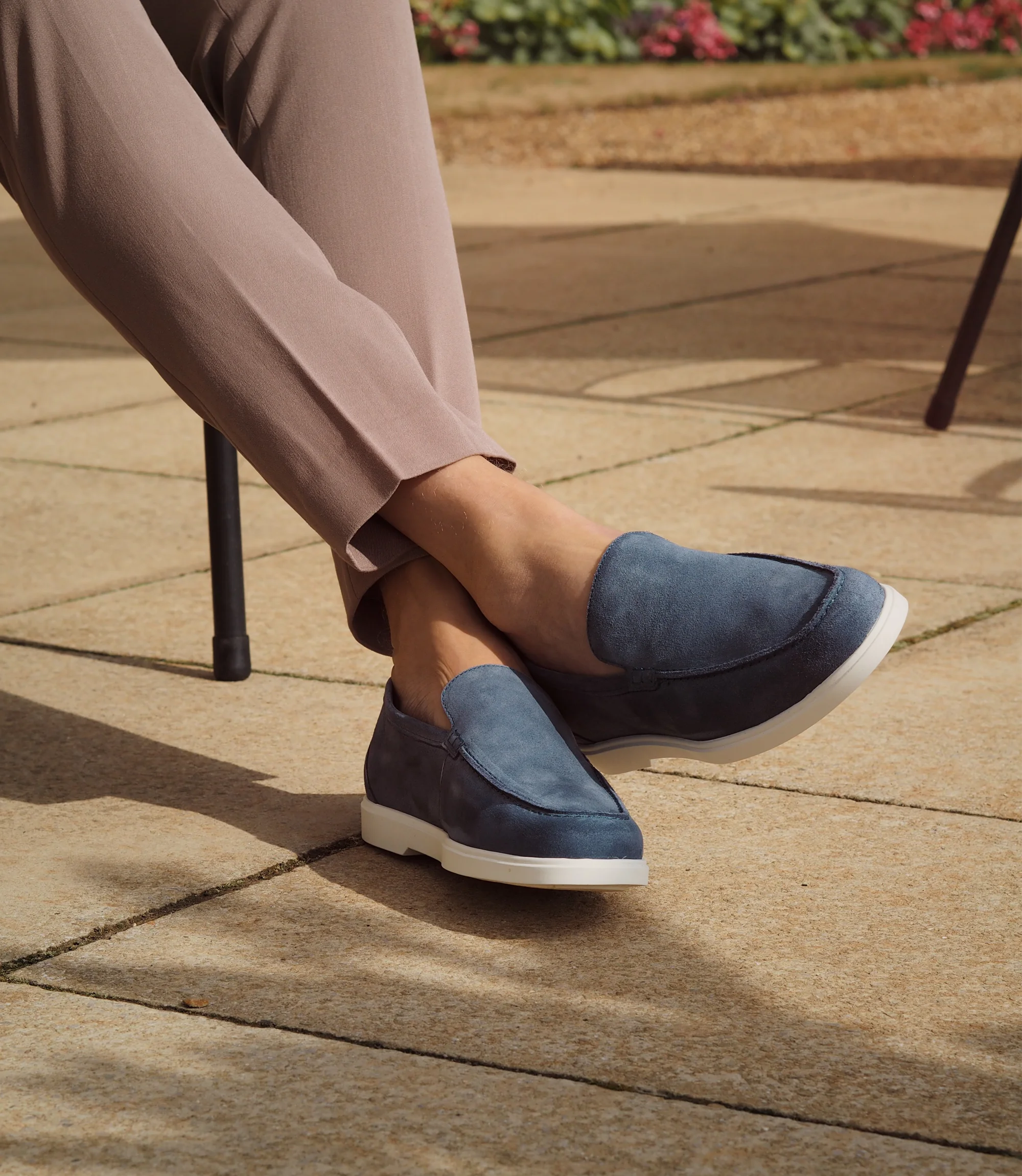 A man sitting down legs crossed on a chair in brown trousers wearing his Loake Tuscany Loafers in Light Blue Suede.
