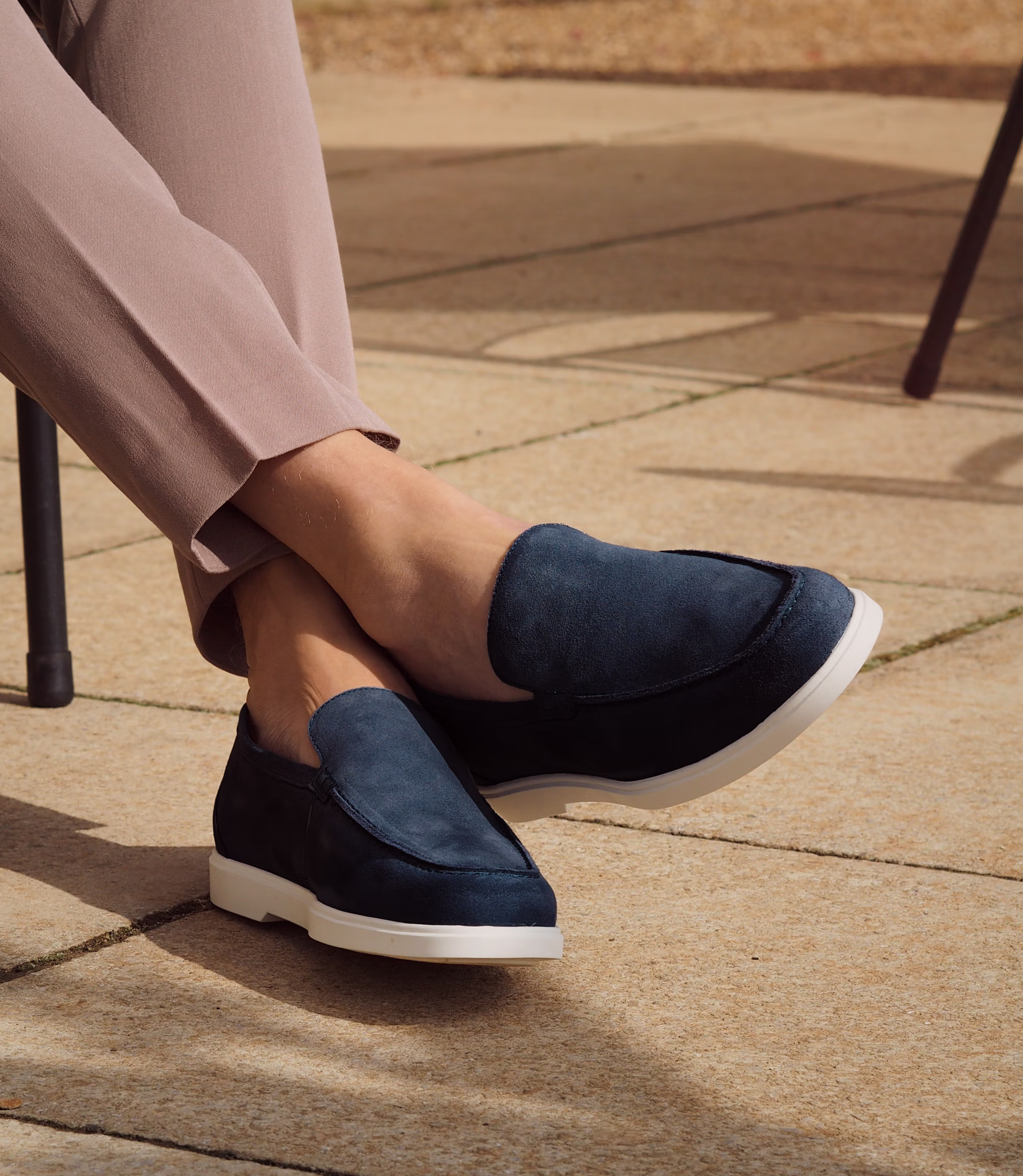 A man sitting down legs crossed on a chair in brown trousers wearing his Loake Tuscany Loafers in Navy Suede.