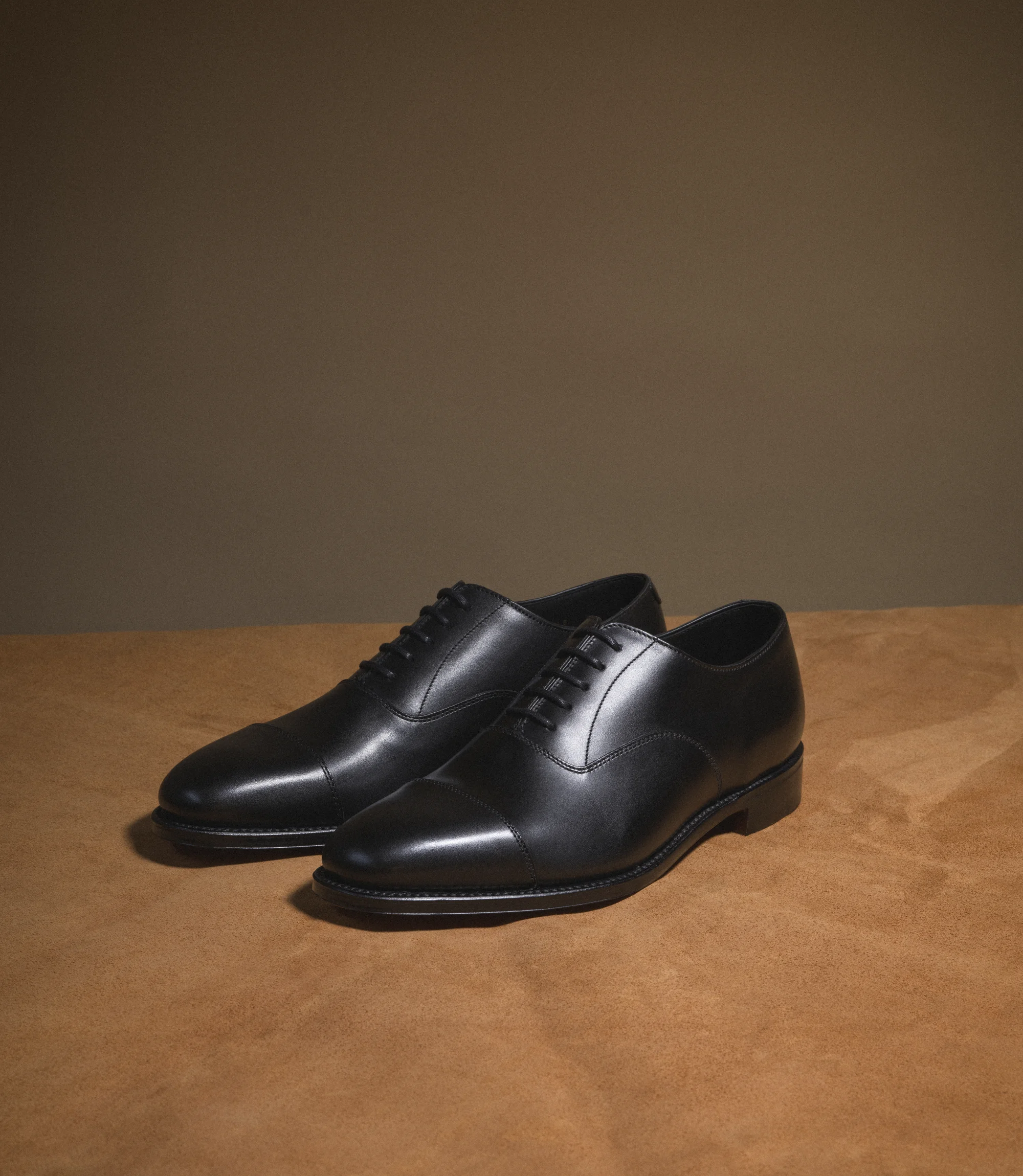 A pair of Loake Aldwych Toe-cap shoes in a studio placed on top of a table as a pair.